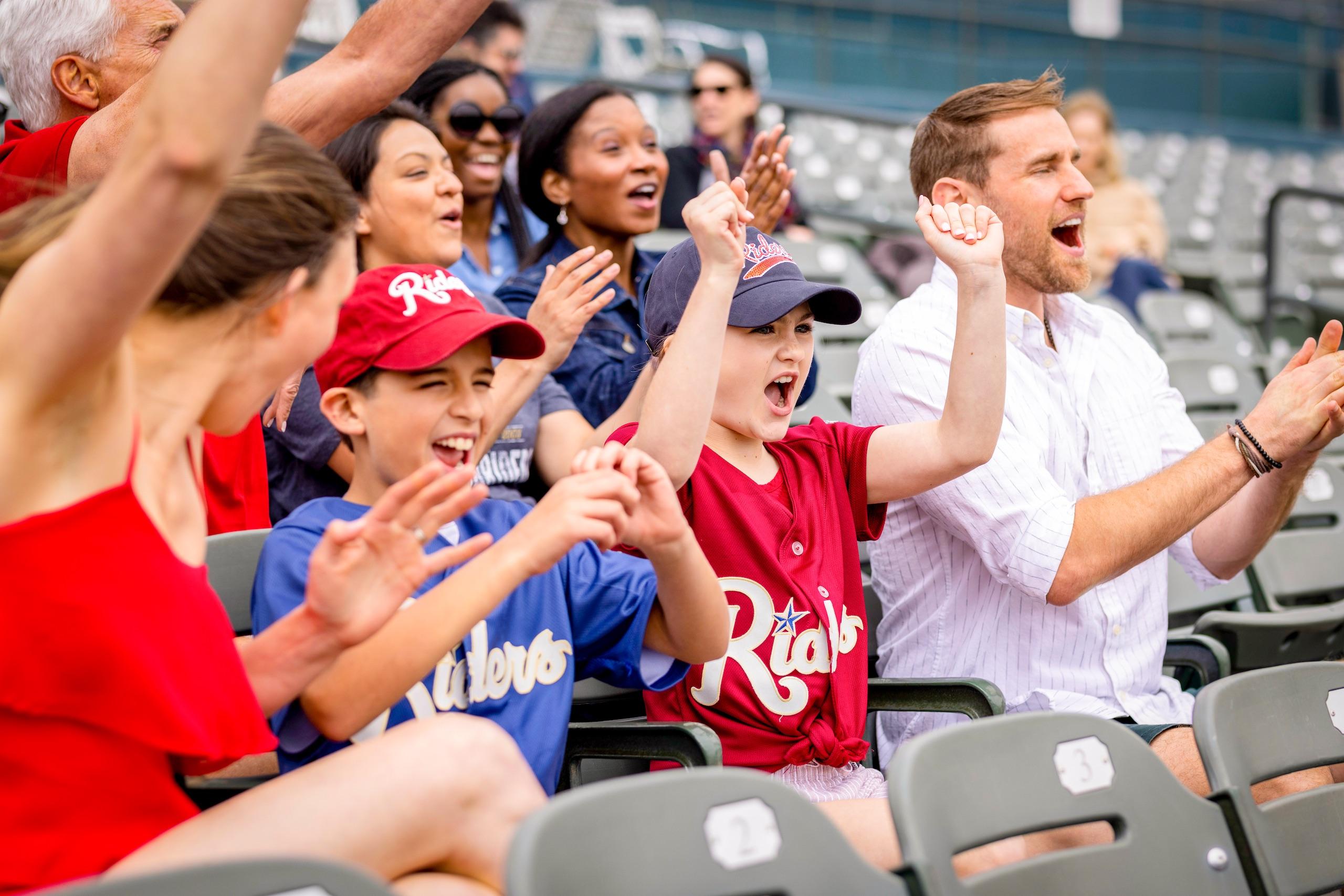 A family clapping and cheering at a baseball game