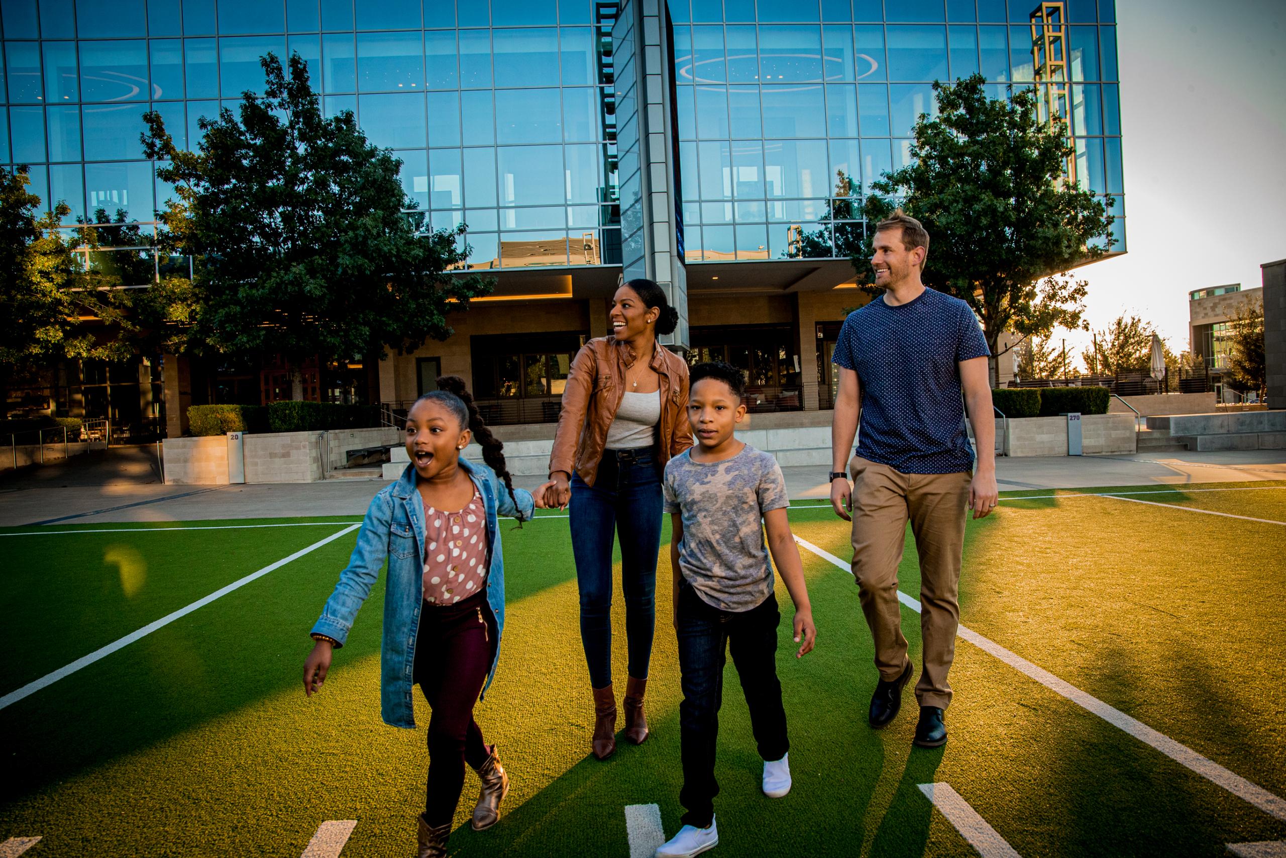A family holding hands and walking onto a football field