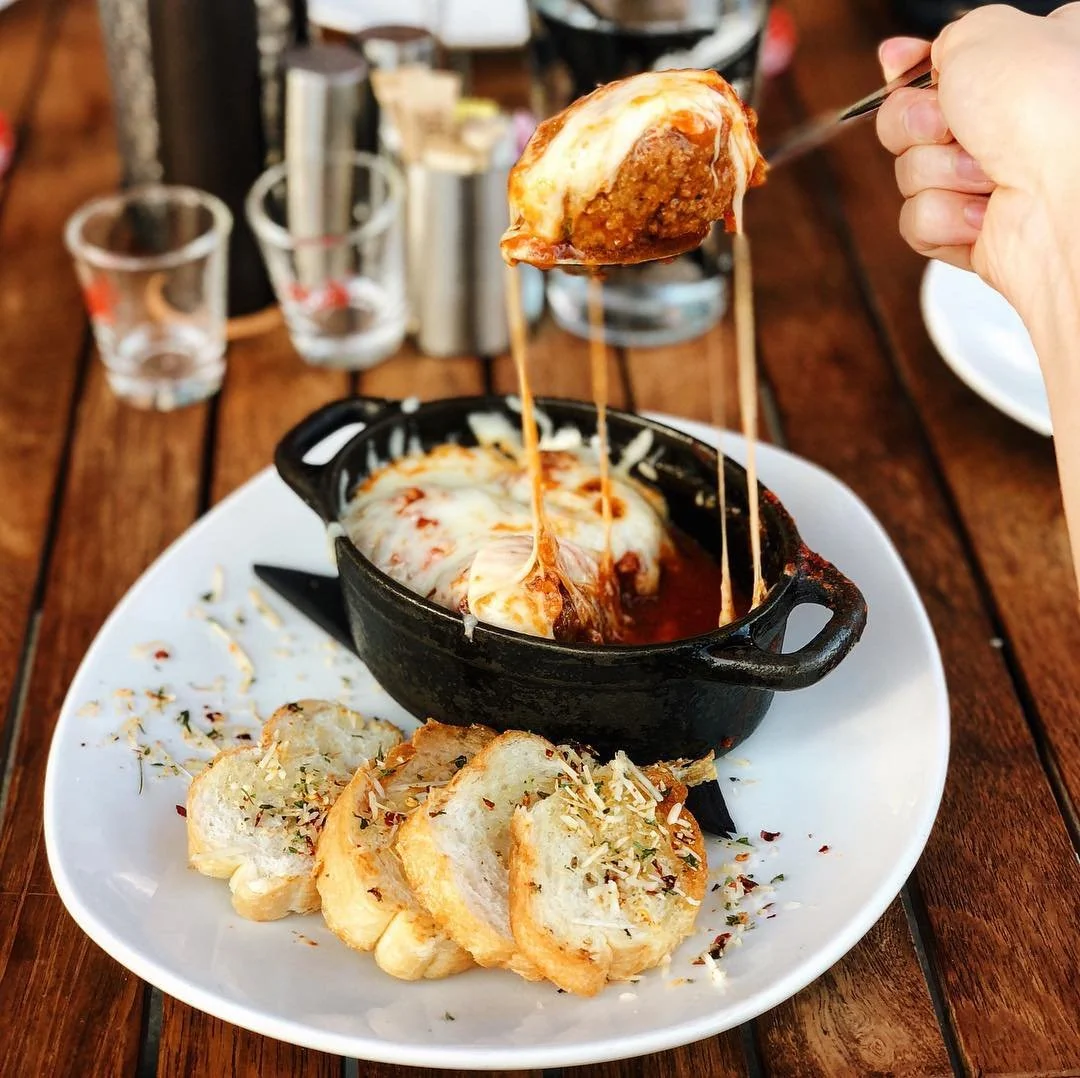 a person lifting a spoonful of food out of a dish