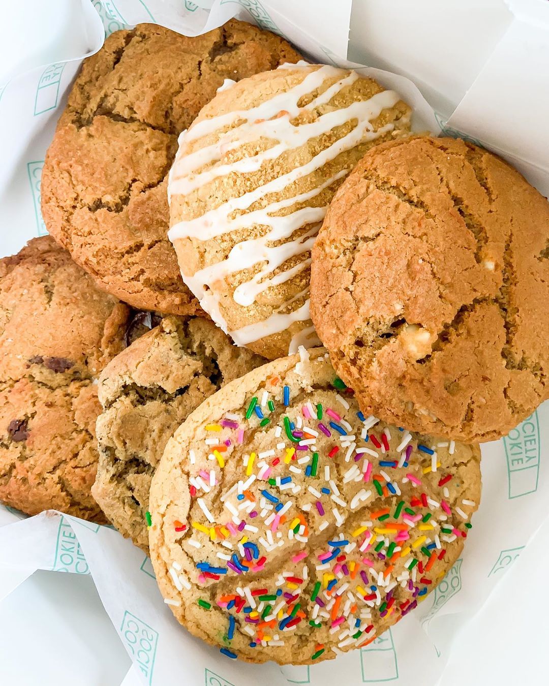 Six different types of cookies resting on a piece of parchment paper