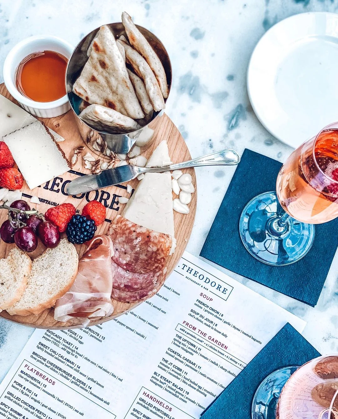 A plate of charcuterie, cheese and bread with a glass of rosé at Theodore
