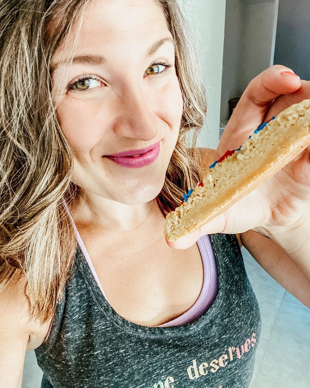 A woman showing a cookie cut in half for social media